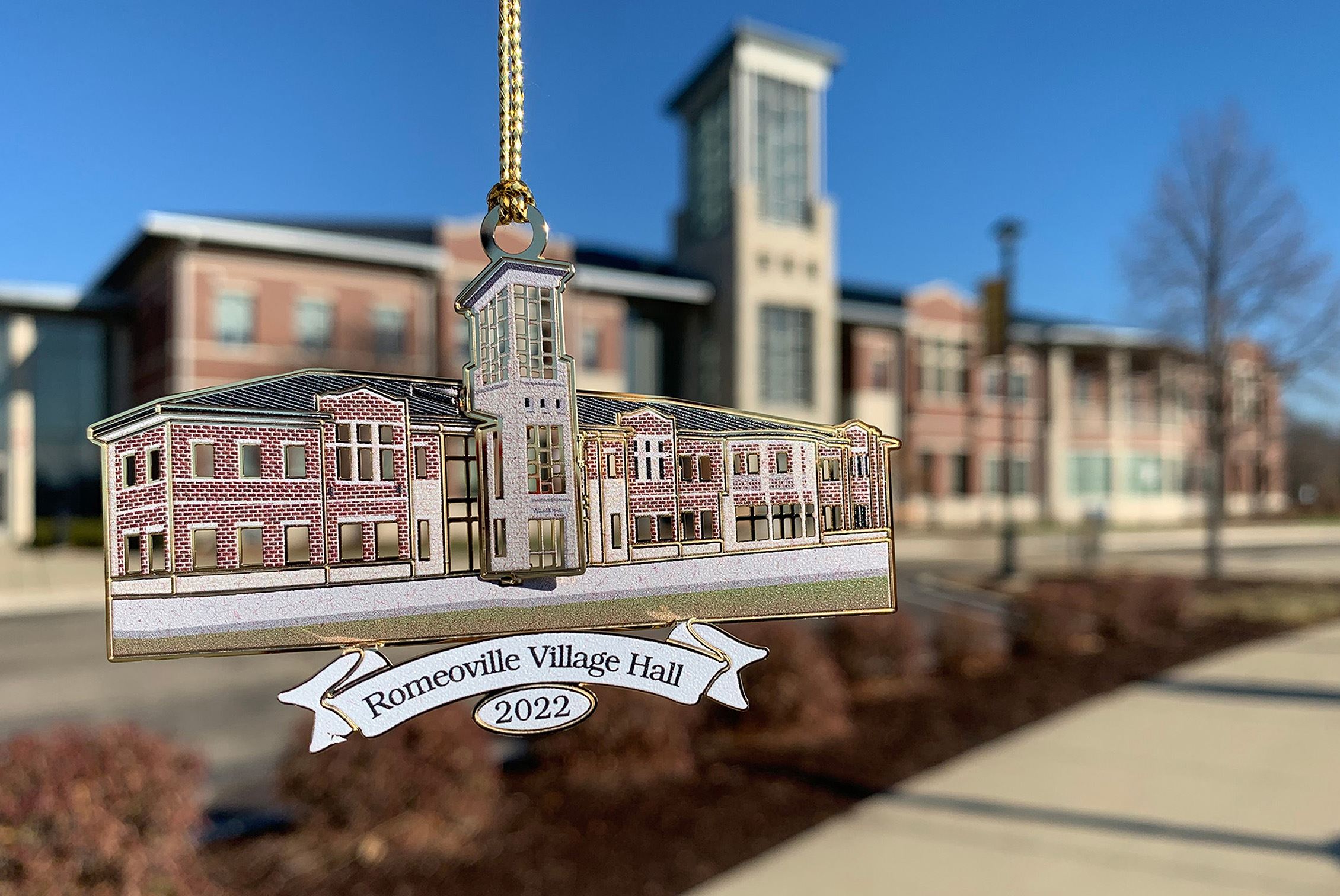 An ornament shaped like Village Hall hangs in front of the actual Village Hall in the background.
